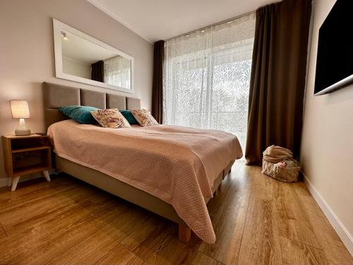 a bedroom with a bed and a large window at Apartament Słoneczny Dziwnów in Dziwnów