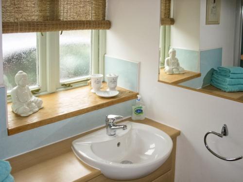 a bathroom with a sink and a mirror and a window at Keepers Cottage in Docking