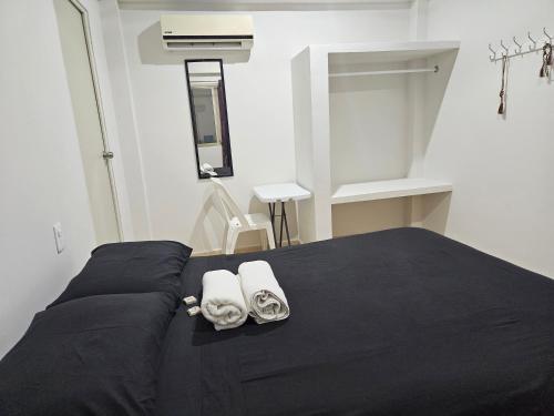 a bedroom with a black bed with towels on it at El Padrino in Akumal
