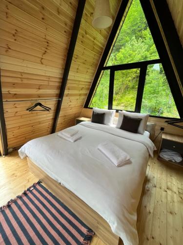 a bed in a room with a large window at GreenWood Cottages Merisi in Merisi