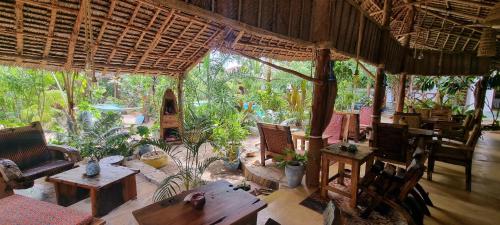 an outdoor patio with tables and chairs and trees at Salama & Mbuyuni Bungalows in Matemwe