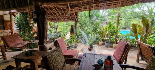 a patio with a table and chairs and a pool at Salama & Mbuyuni Bungalows in Matemwe