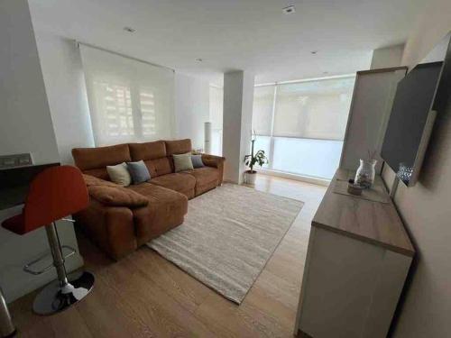 a living room with a brown couch and a television at Precioso apartamento recién reformado in Gijón