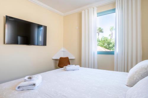 a bedroom with a bed with a tv and a window at Midrahov Luxury Apartment in Zikhron Ya‘aqov