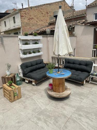 a patio with a table with an umbrella and a couch at Cal Robert in Penellas