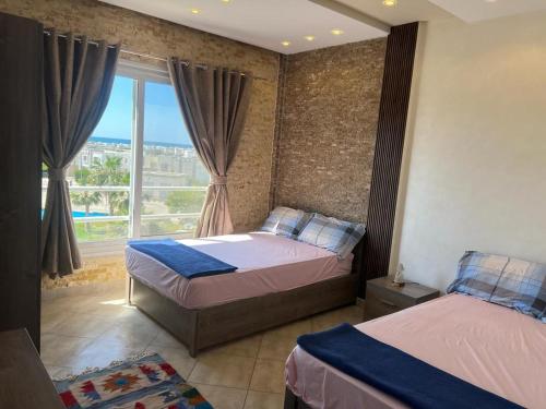 a bedroom with two beds and a large window at Amwaj amazing see view in Marsa Matruh