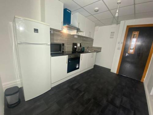 eine Küche mit einem weißen Kühlschrank und einem schwarzen Boden in der Unterkunft Barnet 1 Spacious 2-Bed Apartment in Barnet