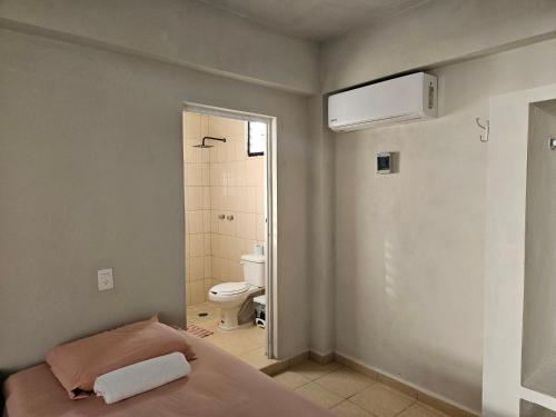 1 dormitorio con 1 cama y baño con aseo en Hostal El Padrino, en Akumal