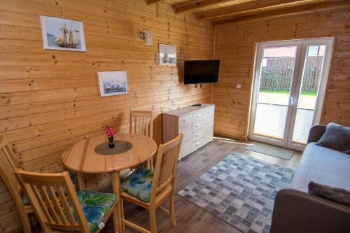 a living room with a table and chairs and a tv at Apartamenty Przy Deptaku in Trzęsacz