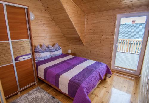 a bedroom with a bed in a wooden room at Apartamenty Przy Deptaku in Trzęsacz