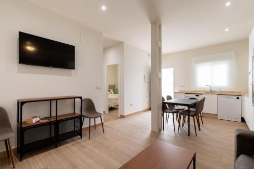 a living room with a table and chairs and a kitchen at Apartamentos Cervantes 17 in Seville
