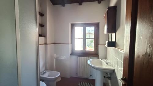 baño con lavabo y aseo y ventana en GreenView - CasaVacanza, en Poppi