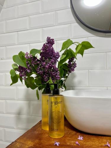 a vase of purple flowers on a table next to a bowl at GreenWood Cottages Merisi in Merisi