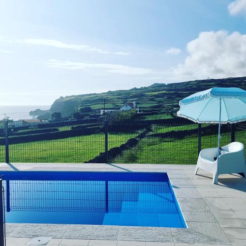 a chair and an umbrella next to a swimming pool at Casa da Torre 2456AL in Angra do Heroísmo