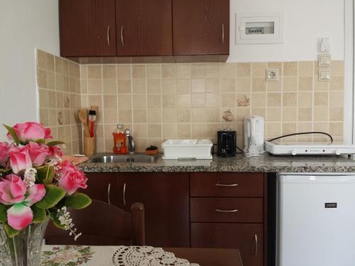 una cucina con lavandino e tavolo con vaso di fiori di Nikos Studios a Kefalos