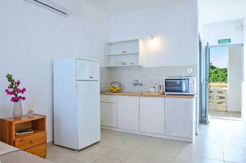 a kitchen with white cabinets and a refrigerator at VIRI VIRI APARTMENTS in Lilikás