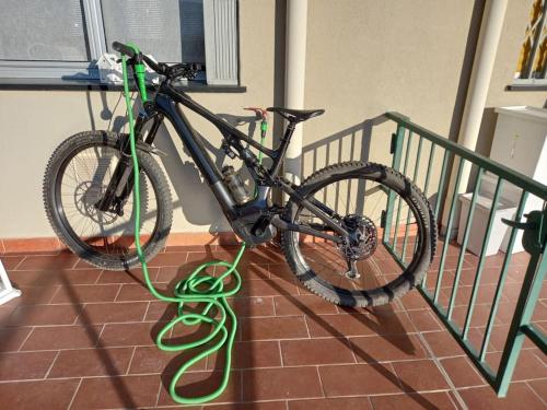 un vélo avec un tuyau vert fixé à un rail dans l'établissement NIDO TRA GLI ULIVI, à Finale Ligure