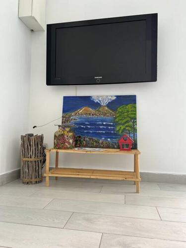 a flat screen tv hanging on a wall with a bench at casa Vesuvio in Cercola