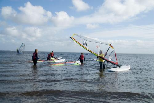 Eine Gruppe von Menschen, die mit einem Segel im Wasser stehen in der Unterkunft Dancamps Holmsland in Hvide Sande