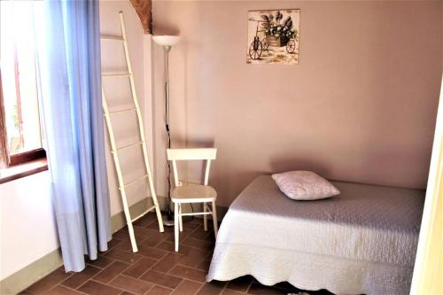niewielka sypialnia z łóżkiem i krzesłem w obiekcie Casa vacanze CLAUDIA 2- SIENA a 10 min w mieście Sovicille