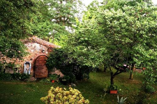 a garden with a brick building and a tree at CLAUDIA VACANZA TOSCANA - Appartamento Melograno -10 min da Siena in Sovicille