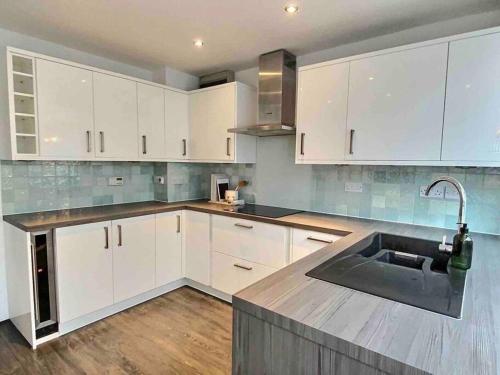 a kitchen with white cabinets and a sink at Home in Solihull - Near NEC, BHX & Solihull Town Centre in Birmingham