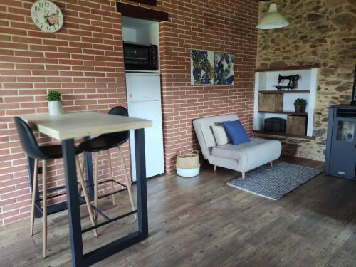 a room with a table and a chair and a brick wall at MINI PICONEIRO II in Pravia