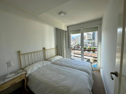 a bedroom with a bed and a large window at Primera Linea Playa de LEVANTE in Benidorm