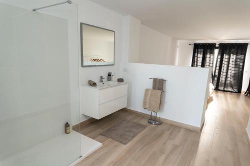 uma casa de banho branca com um lavatório e um espelho em Spacious Duplex with garden in Sotogrande em Sotogrande