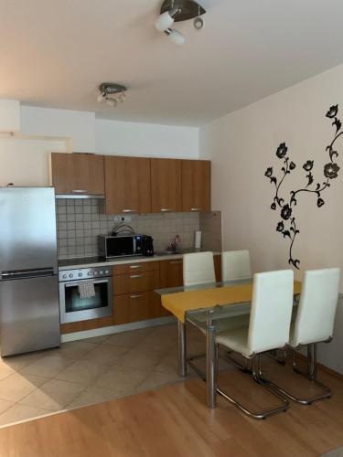 eine Küche mit einem Tisch und einem Kühlschrank aus Edelstahl in der Unterkunft Corvin Fontana Apartment in Budapest