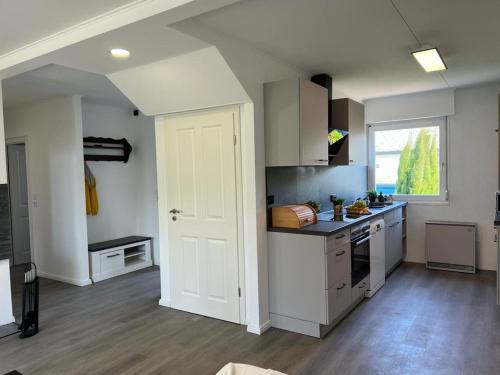 a kitchen with white cabinets and a white door at Strandhaus JP in Maasholm