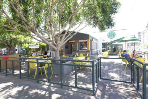 a cafe with yellow tables and chairs and a tree at DTPH Mid Century Studio w/Pool & Parking in Phoenix