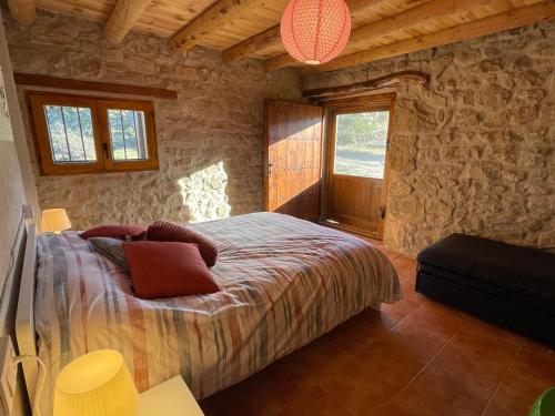 1 dormitorio con cama y pared de piedra en Casa La Rabosa Maella Aragon en Maella
