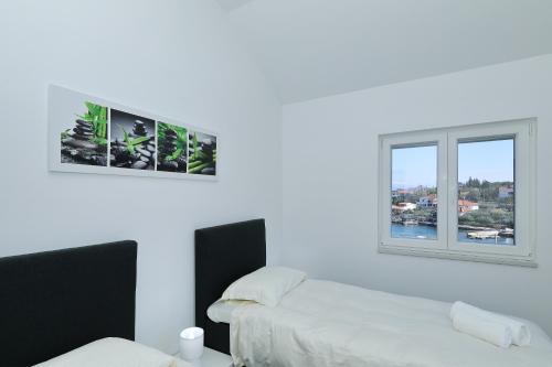 a white room with two beds and a window at Kuca za odmor Davorka in Lukoran