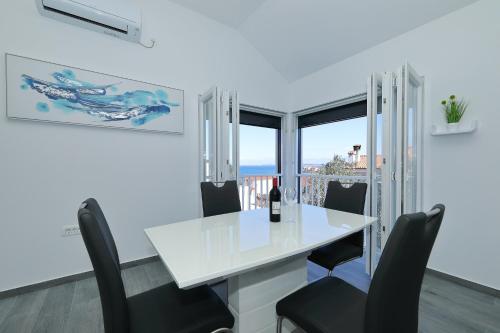 a white dining room with a white table and chairs at Kuca za odmor Davorka in Lukoran