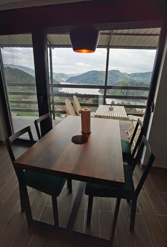 a dining room table with chairs and a large window at Villa Montana Zaovine in Bajina Bašta