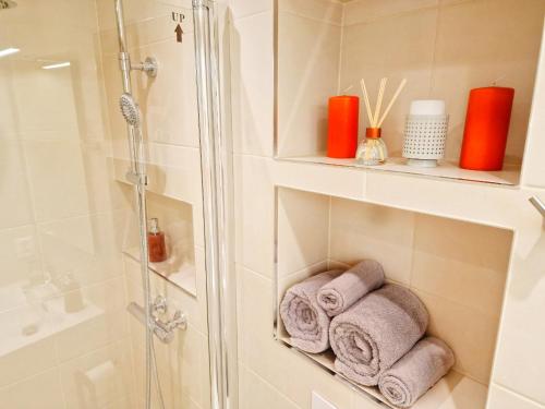 a bathroom with a shower and towels on a shelf at Ibsens apartaments in Bergen