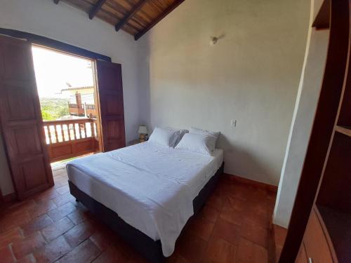 Schlafzimmer mit einem weißen Bett und einem großen Fenster in der Unterkunft La Morada Hospedaje in Barichara