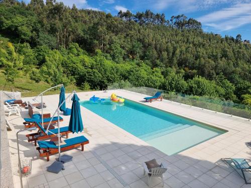a swimming pool with chairs and umbrellas in front of a mountain at Casa de Férias V6 com piscina in Ponte de Lima