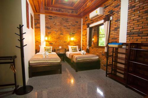 a bedroom with two beds and a brick wall at Hotel Khaosok and Spa in Khao Sok