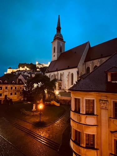 a building with a clock tower and a church at Csaky Palace Bratislava in Bratislava