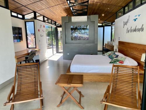 a bedroom with a bed and two chairs at Pacific Kalokairi - Adults Only in Tamarindo