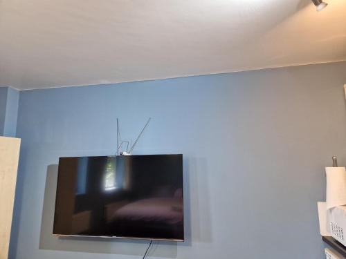 einen Flachbild-TV, der an einer blauen Wand hängt in der Unterkunft Chique Maidstone Studio II in Kent