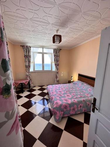 een slaapkamer met een bed en een geruite vloer bij Charmant Appartement vue sur mer in Alger