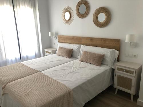 a bedroom with a large bed with two mirrors on the wall at Puerta del Buey Apartamentos in Niebla
