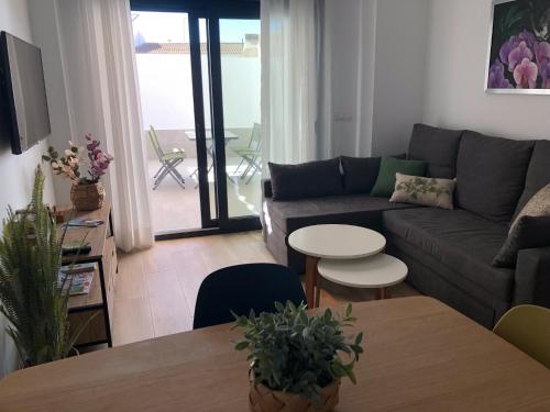 uma sala de estar com um sofá e uma mesa em Puerta del Buey Apartamentos em Niebla