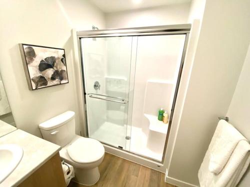 a bathroom with a toilet and a glass shower at Lovely Brand New Condo in Sidney