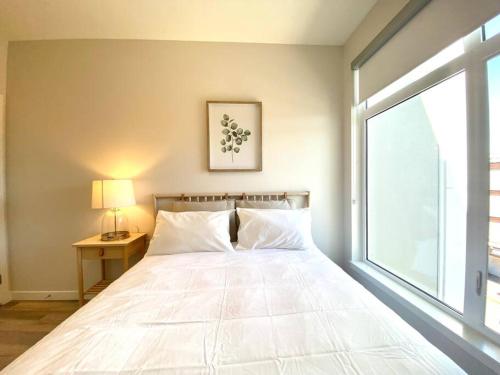 a bedroom with a large white bed with a window at Lovely Brand New Condo in Sidney