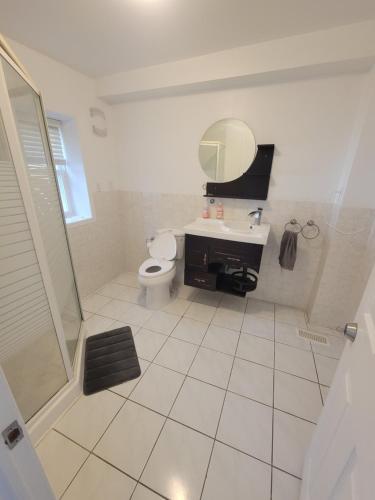 a bathroom with a toilet and a sink and a mirror at 4 Bedroom 3 bathroom 6 queen bed 5 full floor mattress with backyard Whole house for travel or vacation public and celebration group gatherings in Toronto