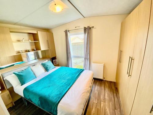 a bedroom with a bed with blue sheets and a window at Modern 6 Berth Caravan At Highfield Grange Near Clacton-on-sea Ref 26302e in Clacton-on-Sea